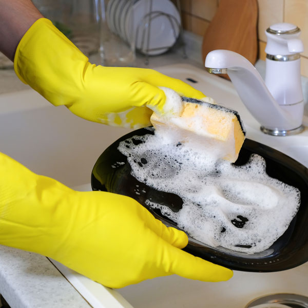 closeup of individual cleaning a plate with soap and water