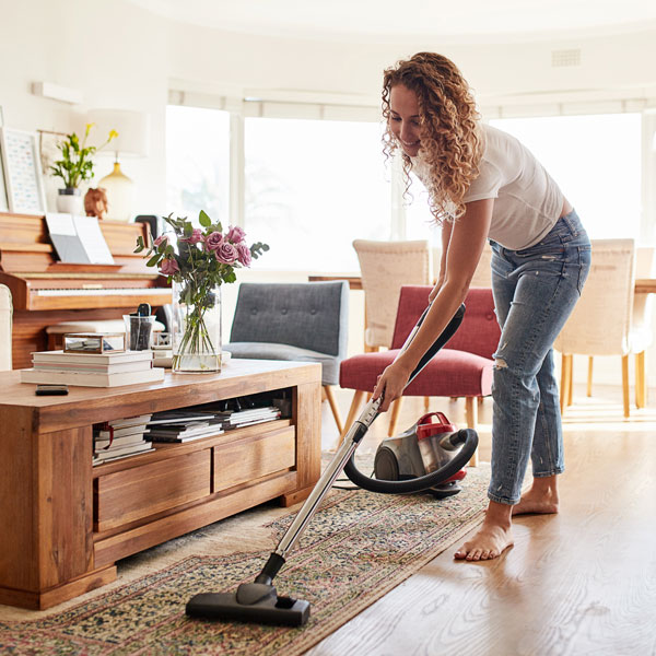 A woman vacuuming an area rug inside their home