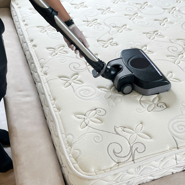 closeup of a vacuum on top of a mattress to clean of any dust and debris