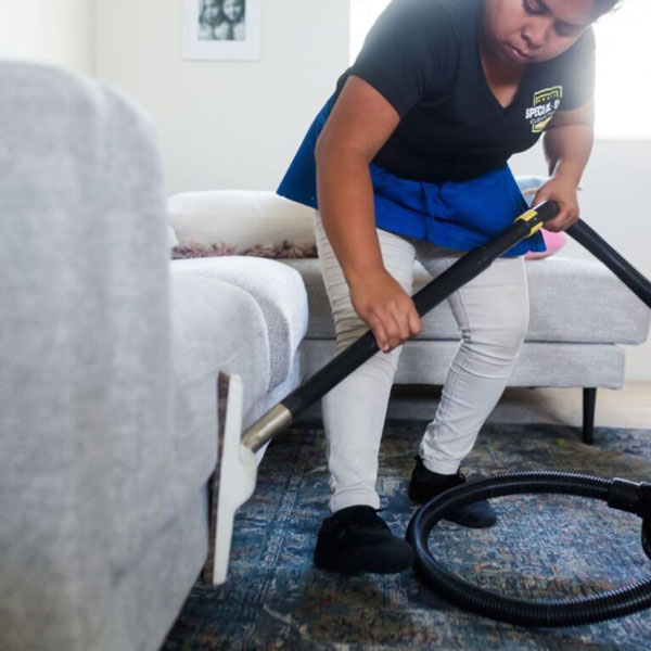 A Special Ops Clean Team member vacuuming the side of a sofa in the Phoenix, AZ area